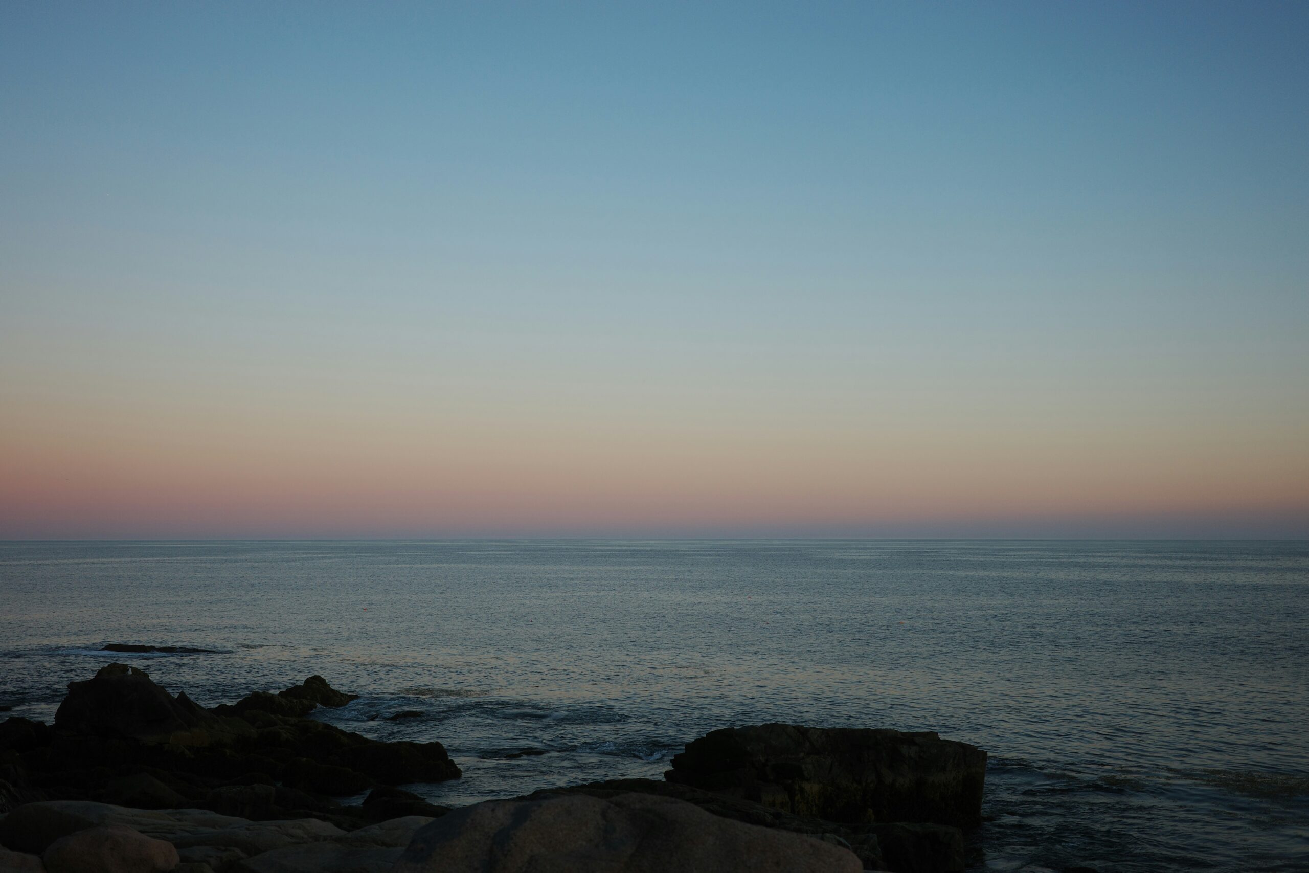 A calm ocean horizon under a soft pastel sky at dusk