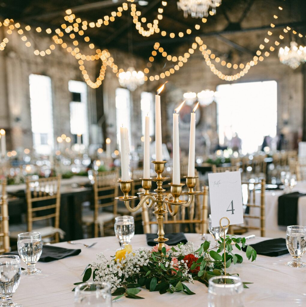 Wedding reception table set with a lit gold candelabra
